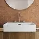 Waschtisch in Weiß von Ideal Standard mit gerader Form, ausgestattet mit einem modernen Wasserhahn und zwei separaten Verchromten Griffen, vor einer Korkwand montiert.